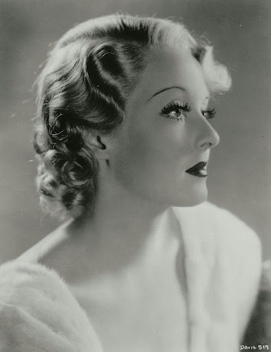 Foto da atriz estadunidense Bette Davis, em preto e branco, destacando os seus cabelos loiros com finger waves.