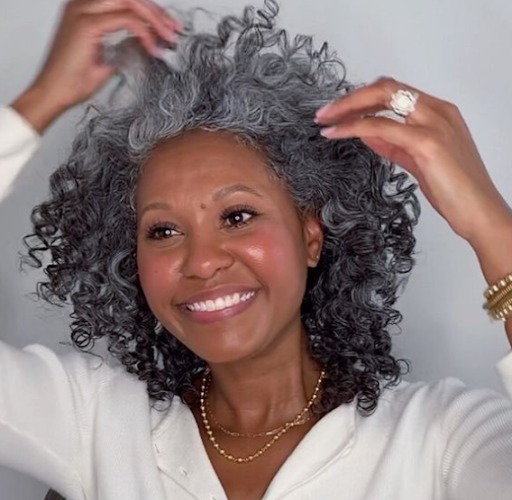 Grey Blending: mulher negra, de cabelos cacheados grisalhos, posa para foto.