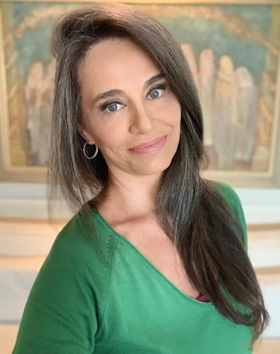 Grey Blending: a jornalista Carla Vilhena, da CNN Brasil, posa para foto, com quadro ao fundo, de blusa verde e cabelos grisalhos. 