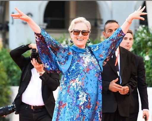 Grey Blending: a atriz norte-americana Meryl Streep acena para os fãs, enquanto veste um vestido azul estampado, e arrasa com seus cabelos loiros e grisalhos.