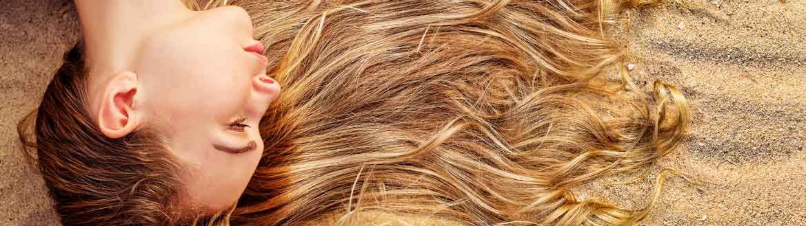 Jovem mulher com cabelo ruivo ondulado volume longo projeto rapunzel em fundo cinza.