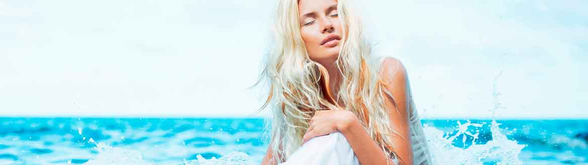 Mulher no mar com cabelo loiro praia platinado, ondulado finalização beach waves e roupa branca.