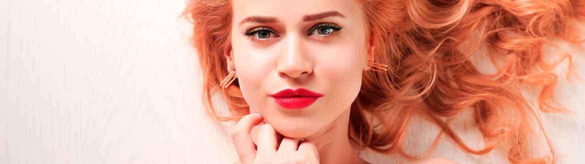 Mulher jovem com batom vermelho e cabelo cacheado com cabelo rosa cor tendência cherry blonde strawberry blonde