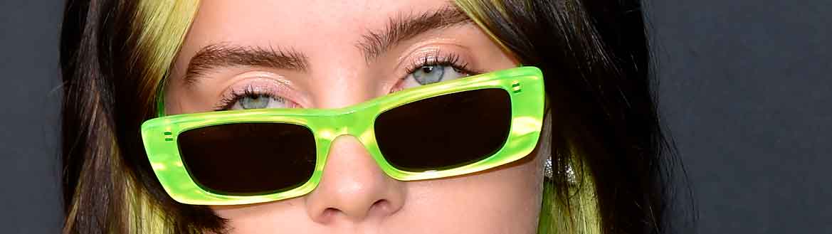 Billie Eilish em premiação com cabelo, óculos e roupa verde neon, tendência geração Z e-girl