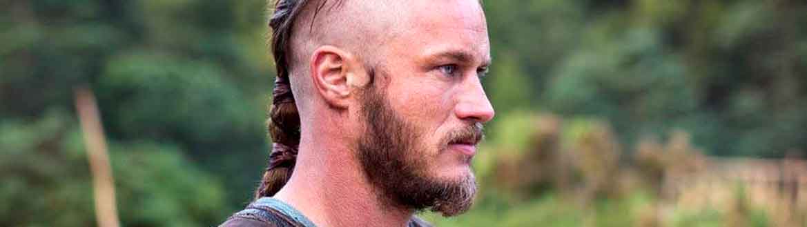 Ragnar Lothbrock, da série Vikings, olhando para o lado em momento de batalha, com trança viking no cabelo