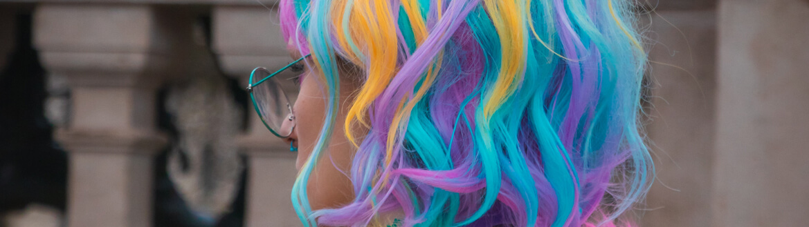 Mulher jovem de cabelo multicolorido e roupa divertida em fundo urbano